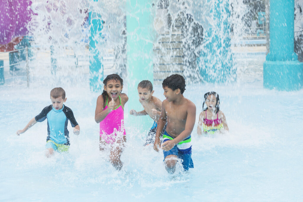 multi ethnic children playing in falling water at park