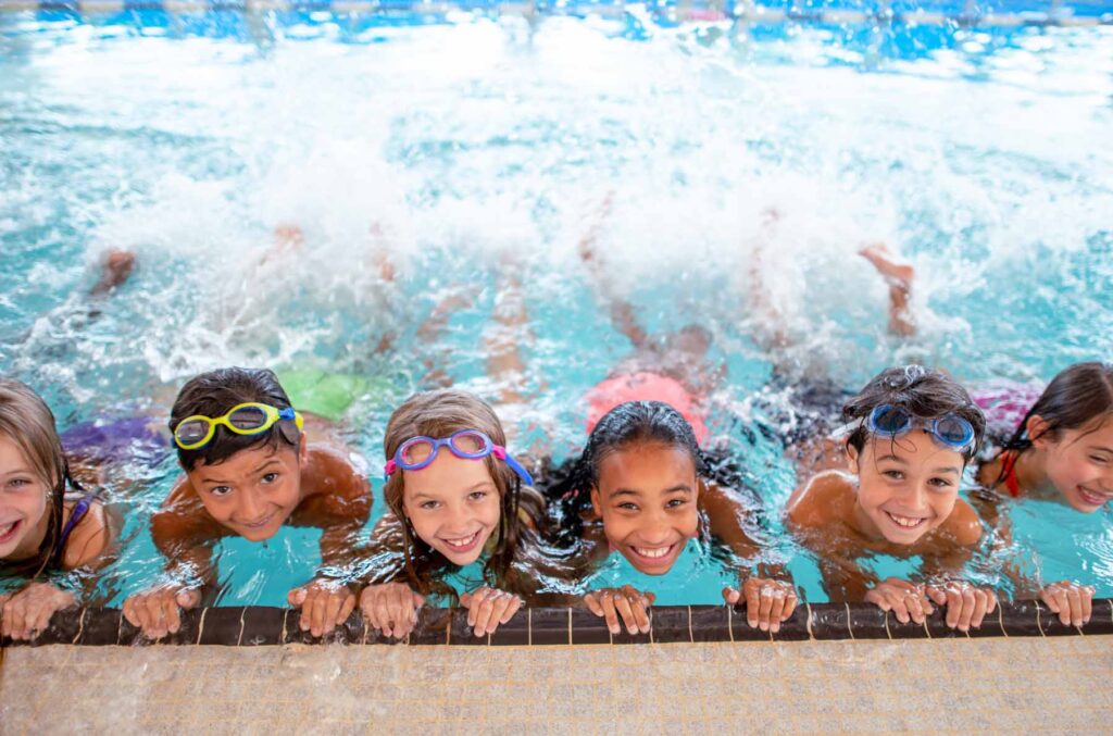 multi ethnic group of children learning to kick in the swimming pool, Commercial Pool Heating